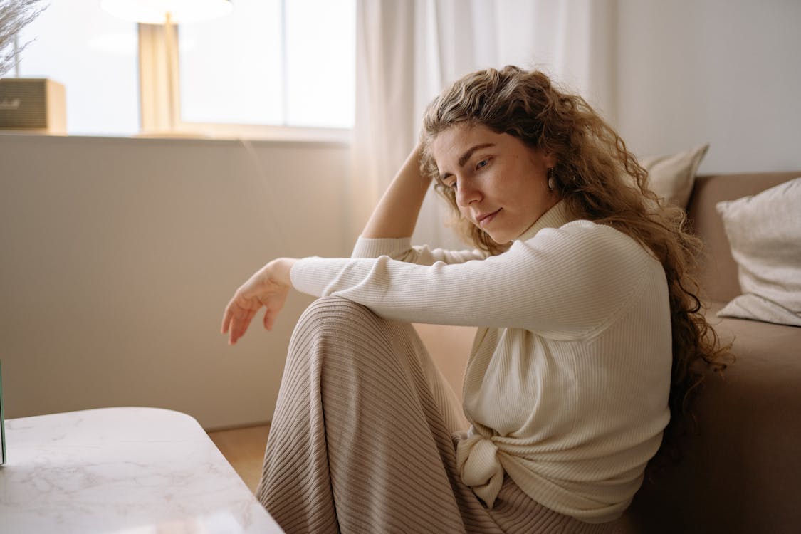 Person sitting alone in a calm, warmly lit living room, peacefully using their phone — representing low-pressure connection for people with social anxiety