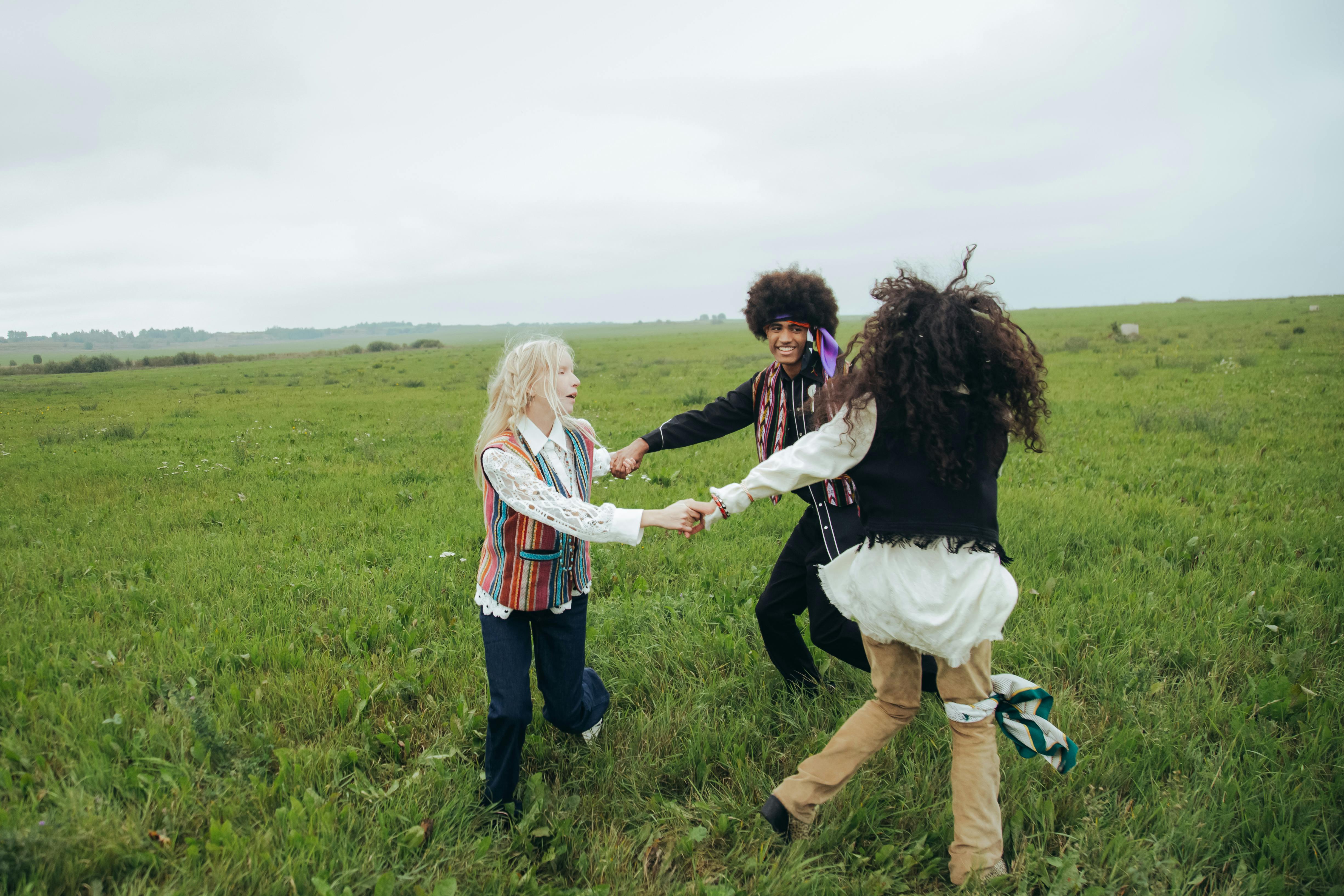 Three people holding hands and spinning together in a bright green field