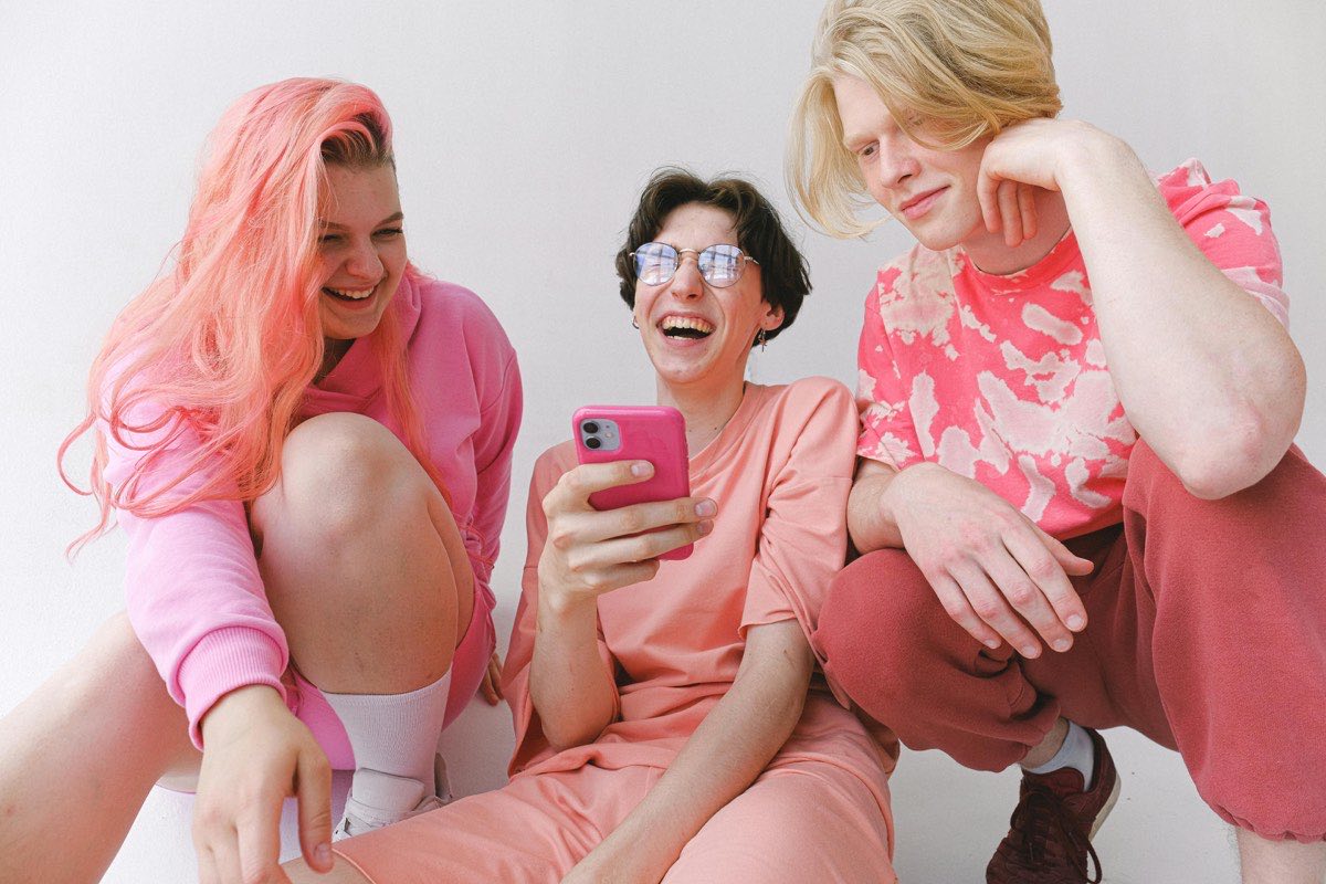 Two women laughing together while looking at a phone