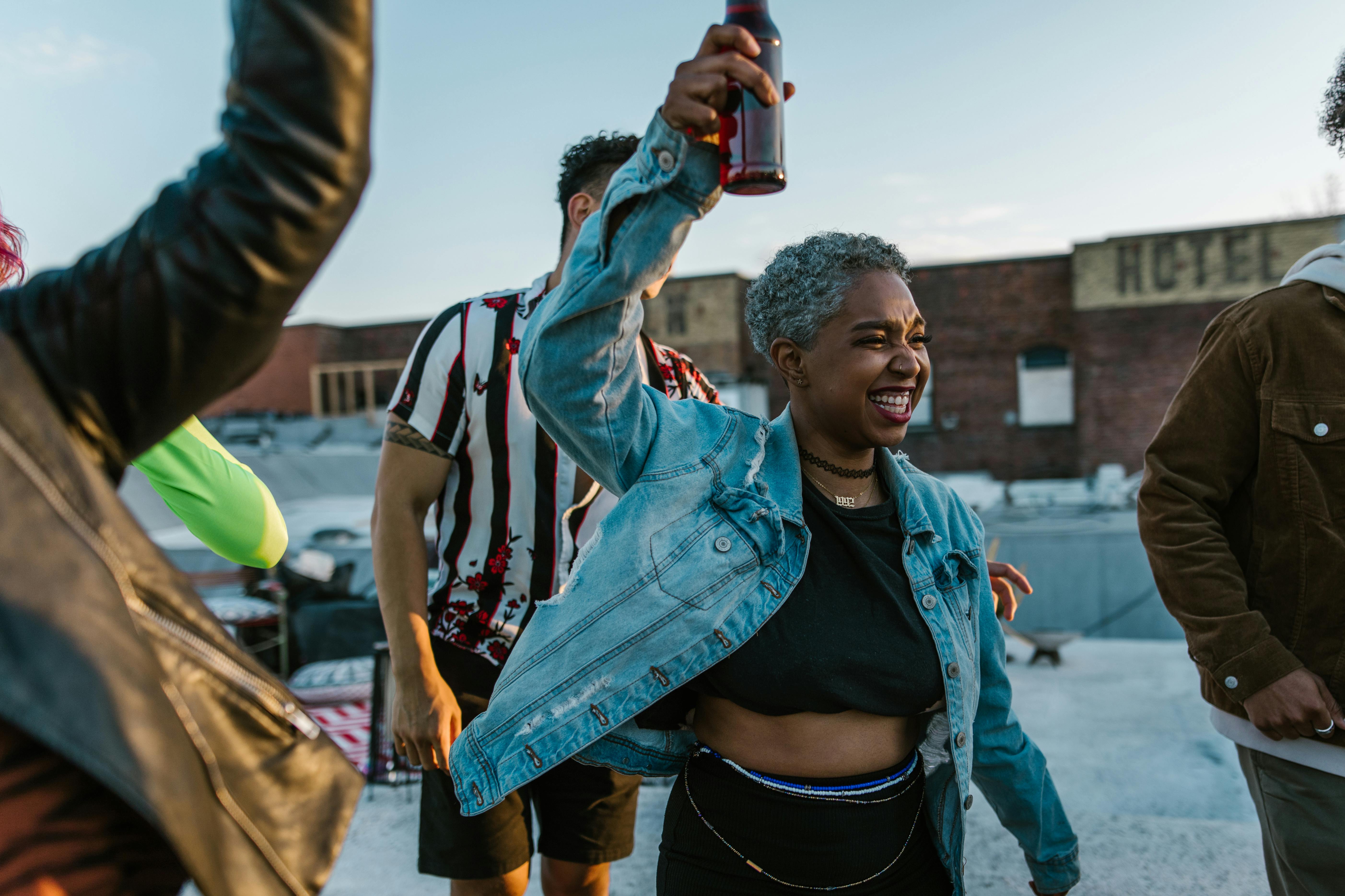 Woman with silver hair dancing joyfully at a rooftop party with friends