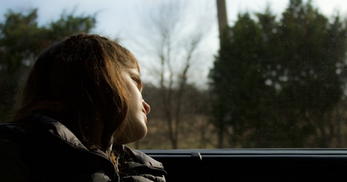 Young person gazing out a car window in quiet contemplation