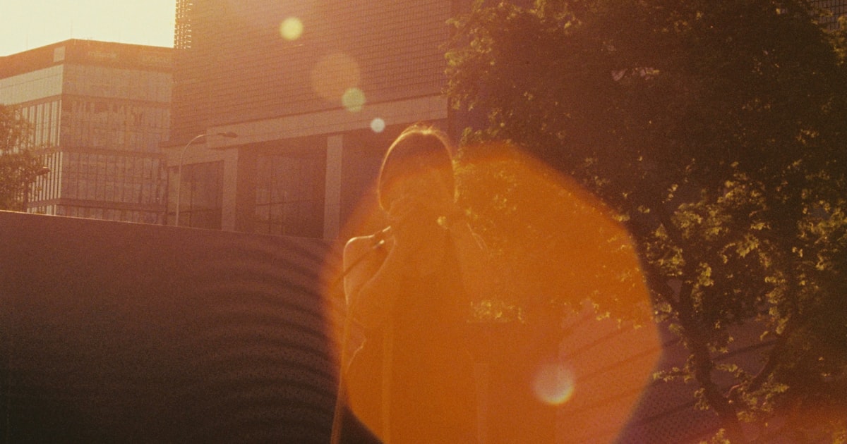 Two people walking together in sunlight near urban buildings