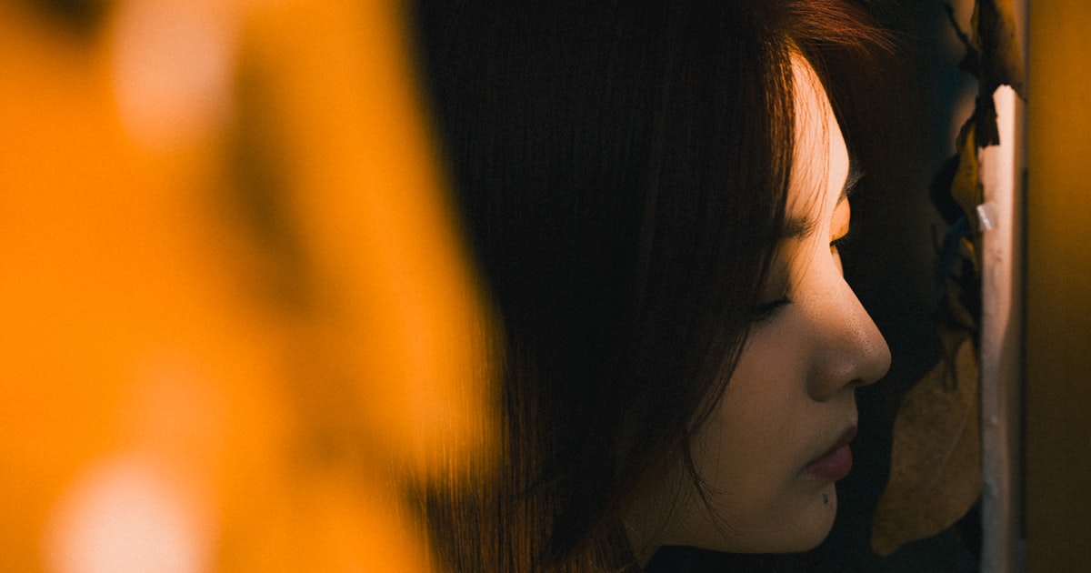 Young woman looking out a window at night, quiet and introspective