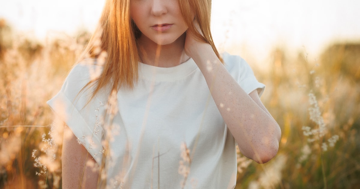 Young woman posing in a field of tall grass, editorial portrait