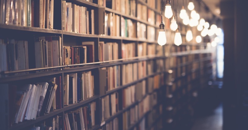Sunlit aisle of a library, shelves of books on both sides
