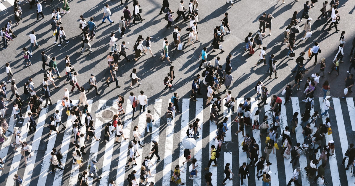 Aerial view of hundreds of people walking across a busy city crossing