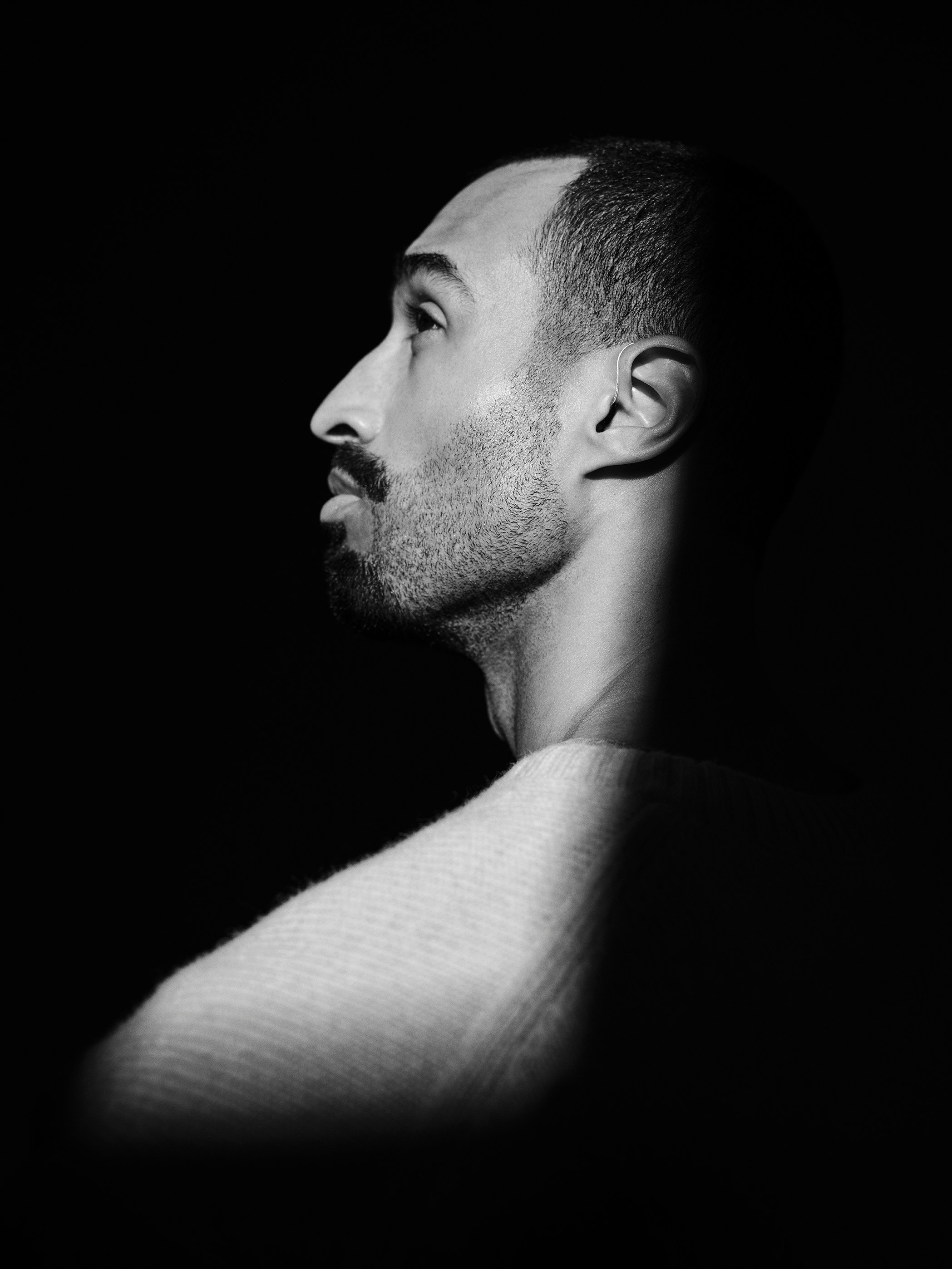Black and white dramatic portrait of a man against a dark background