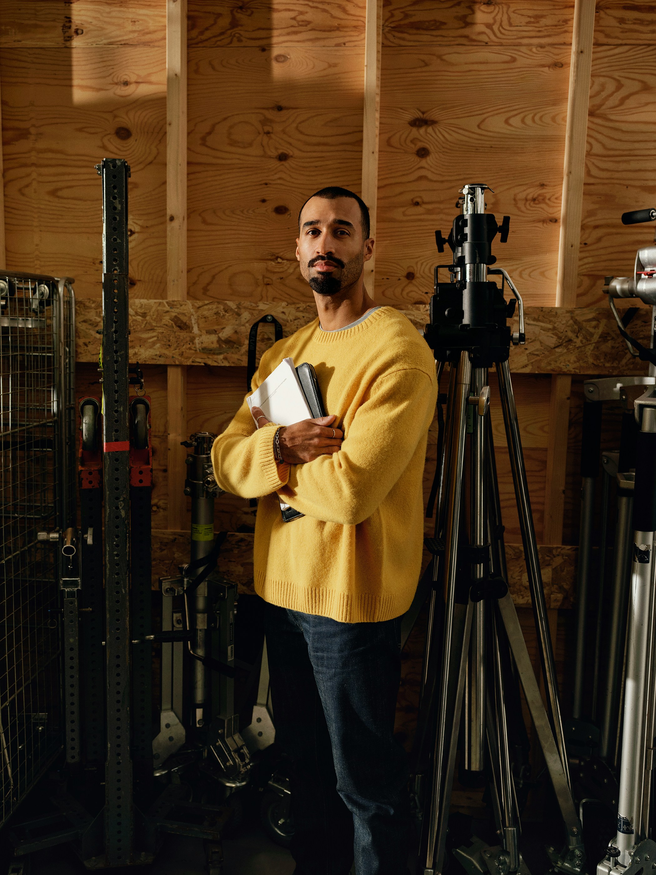 Man in a yellow sweater in a workshop or studio, thoughtful and focused