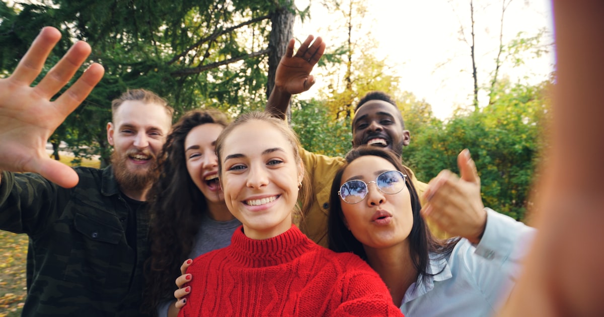 Group of young women friends taking a selfie together outdoors, laughing